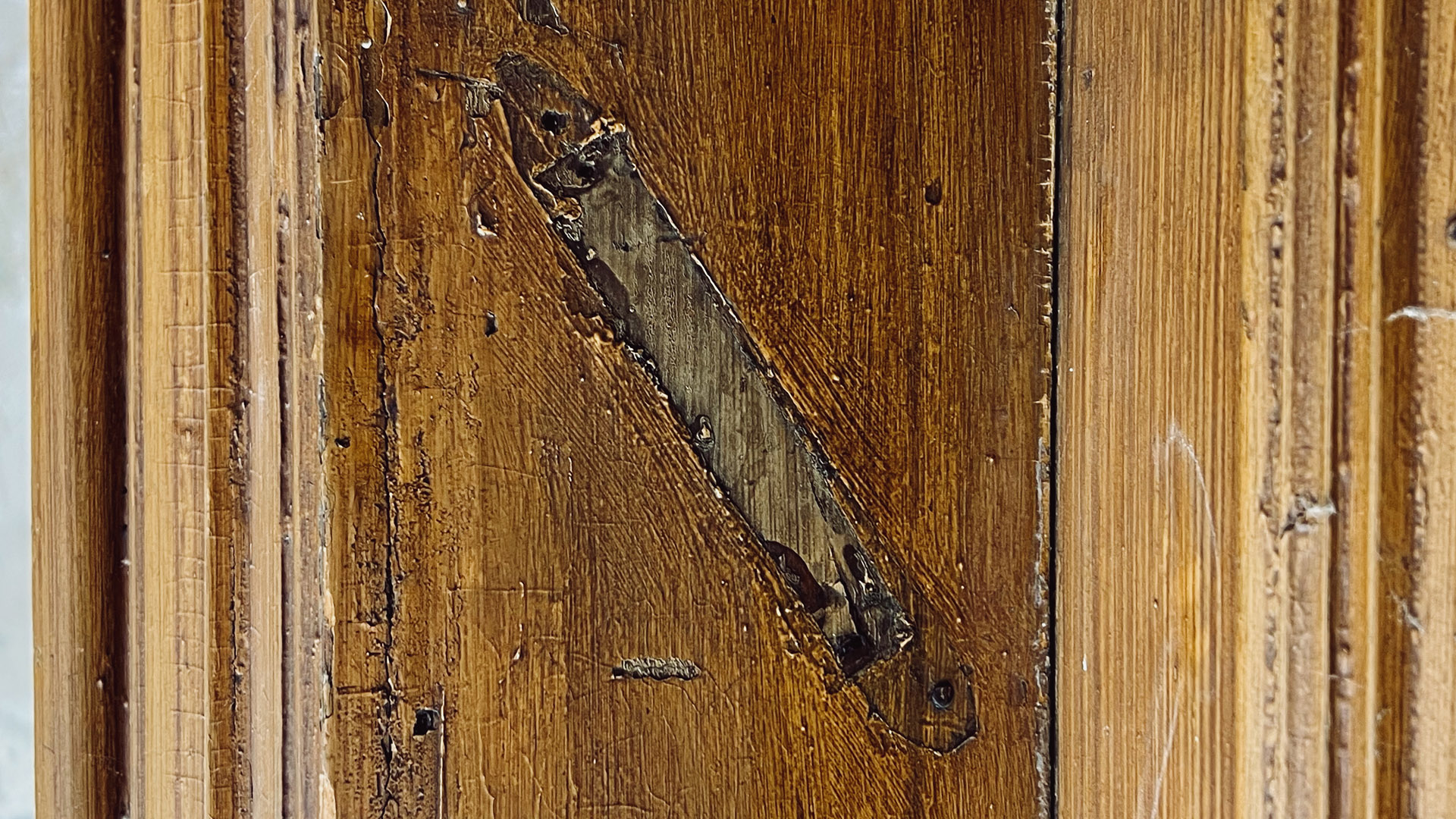 A close-up of a wooden door panel with deep scratches, revealing rough wood beneath—perfect for displaying the MEZUZAH KRAKOW JÓZEFA 14 ST.—with smaller scratches and worn areas adding character. mezuzah trace kraków