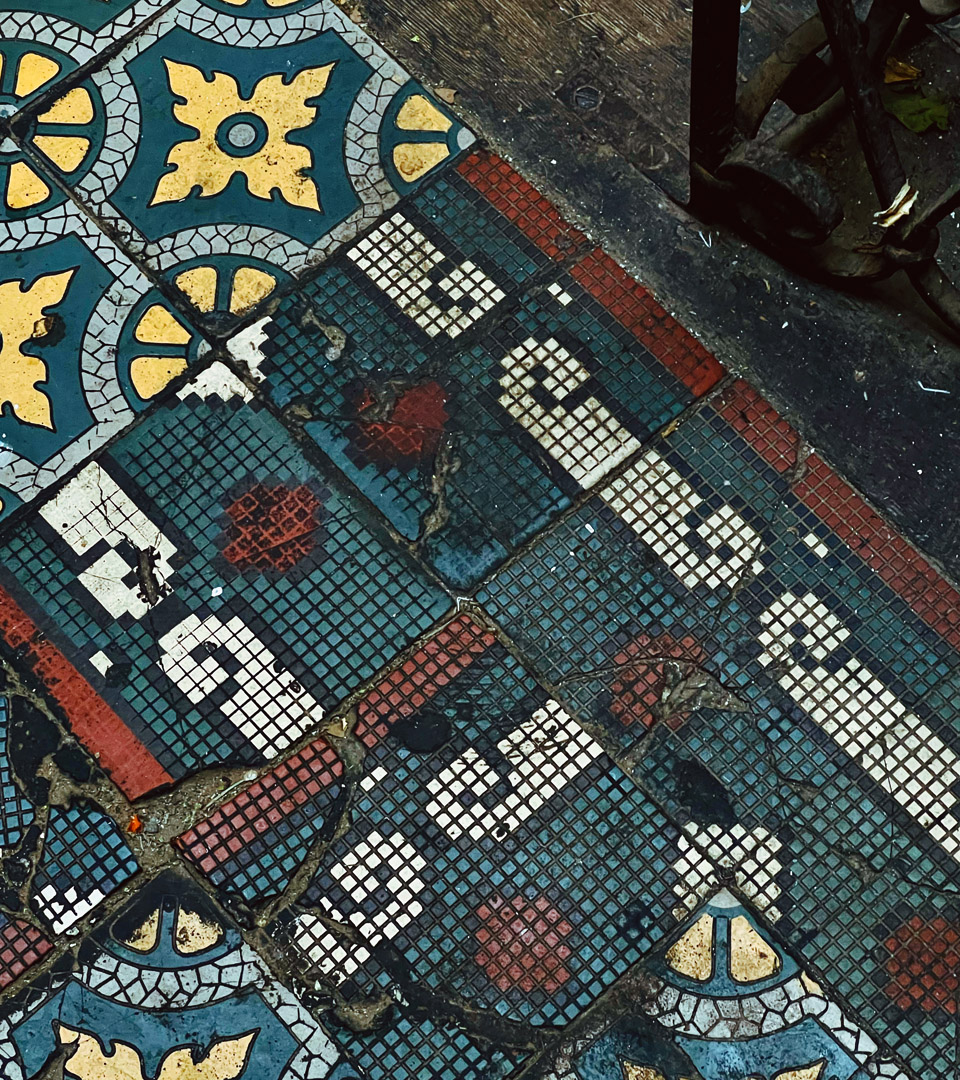 Colorful vintage tiles with geometric and floral patterns evoke Krakow’s charm; some are faded or cracked. A MEZUZAH KRAKOW JÓZEFA 14 ST. by Mi Polin lies in the corner, adding a unique touch to the scene.