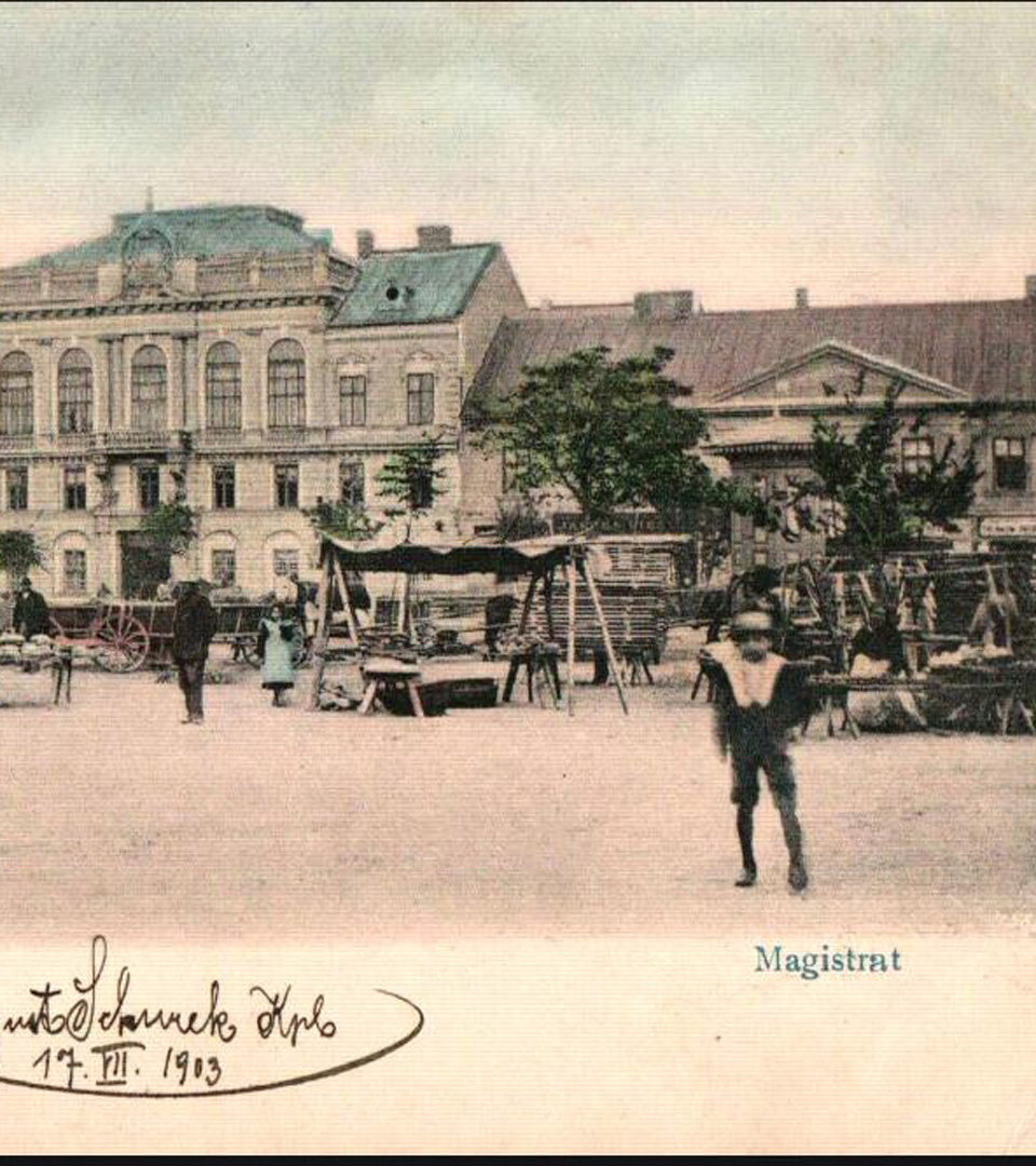 A vintage postcard of MEZUZAH, Krakow Rynek Podgórski 2, shows market stalls, people walking, and a large building in the background. A child runs in front. The signed card dates to 1903 and reflects rich Judaica history.
