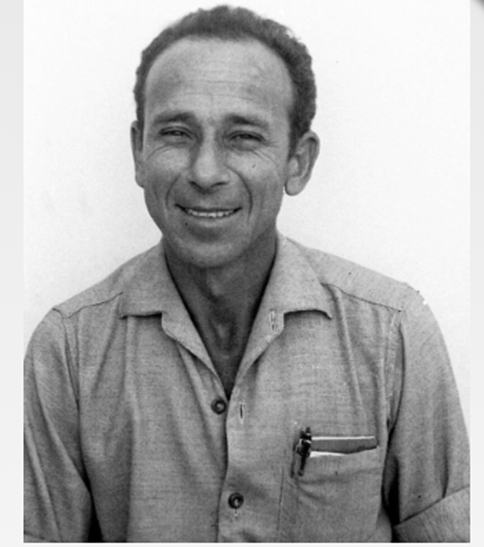 A man with short curly hair smiles at the camera in a light button-up shirt with pens in the pocket. This portrait appears in a Judaica exhibit for the MEZUZAH Krakow Józefa 14 St., set against a plain white background.