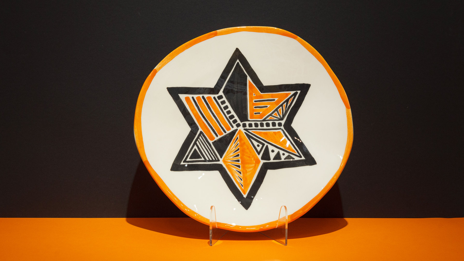 Star of David. The ceramic plate was treated as a painting. The Star of David was hand-painted by Helena Czernek co-designer MI POLIN, who, together with Aleksander Prugar, developed the unique painting patterns. The plates painting are inspired by the Cubist style and Polish graphic design of the 1960s and 1970s. Made at MI POLIN and entirely manufactured in Poland.