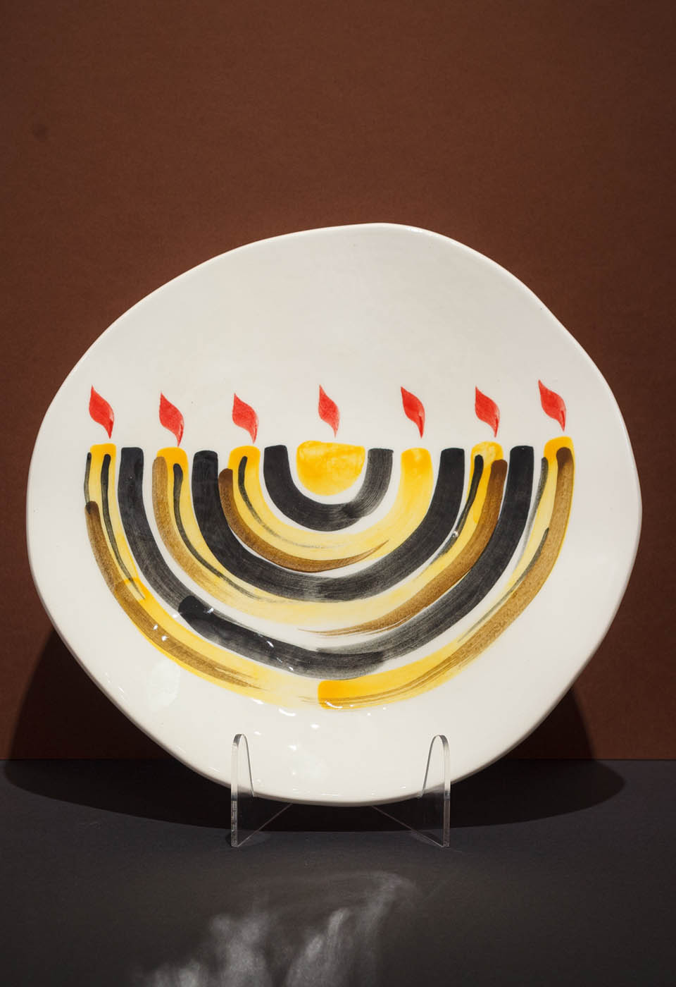 Menorah plate. The ceramic plate was treated as a painting. Menorah plate was hand-painted by Helena Czernek co-designer MI POLIN, who, together with Aleksander Prugar, developed the unique painting patterns. The plates painting are inspired by Polish graphic design of the 1960s and 1970s. This refers to the pottery factories of Włocławek and Tułowice. Made at MI POLIN and entirely manufactured in Poland.