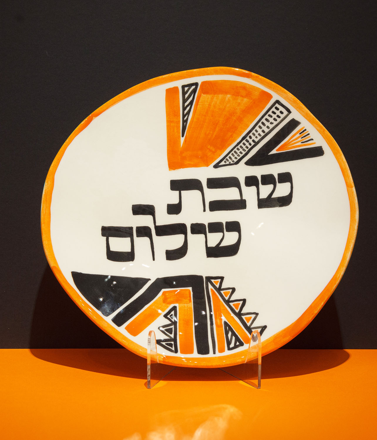 Hand-calligraphed Hebrew inscription "Shabbat Shalom" on a decorative Jewish plate