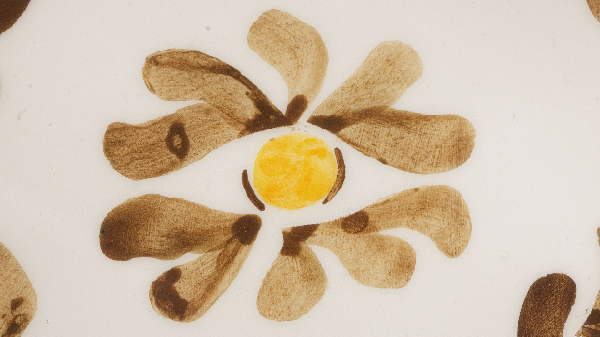 A close-up of a hand-painted plate with a HAMSA plate. Hand-painted Jewish Judaica. Brushstrokes and ceramic glaze are visible. Highly precise craftsmanship.