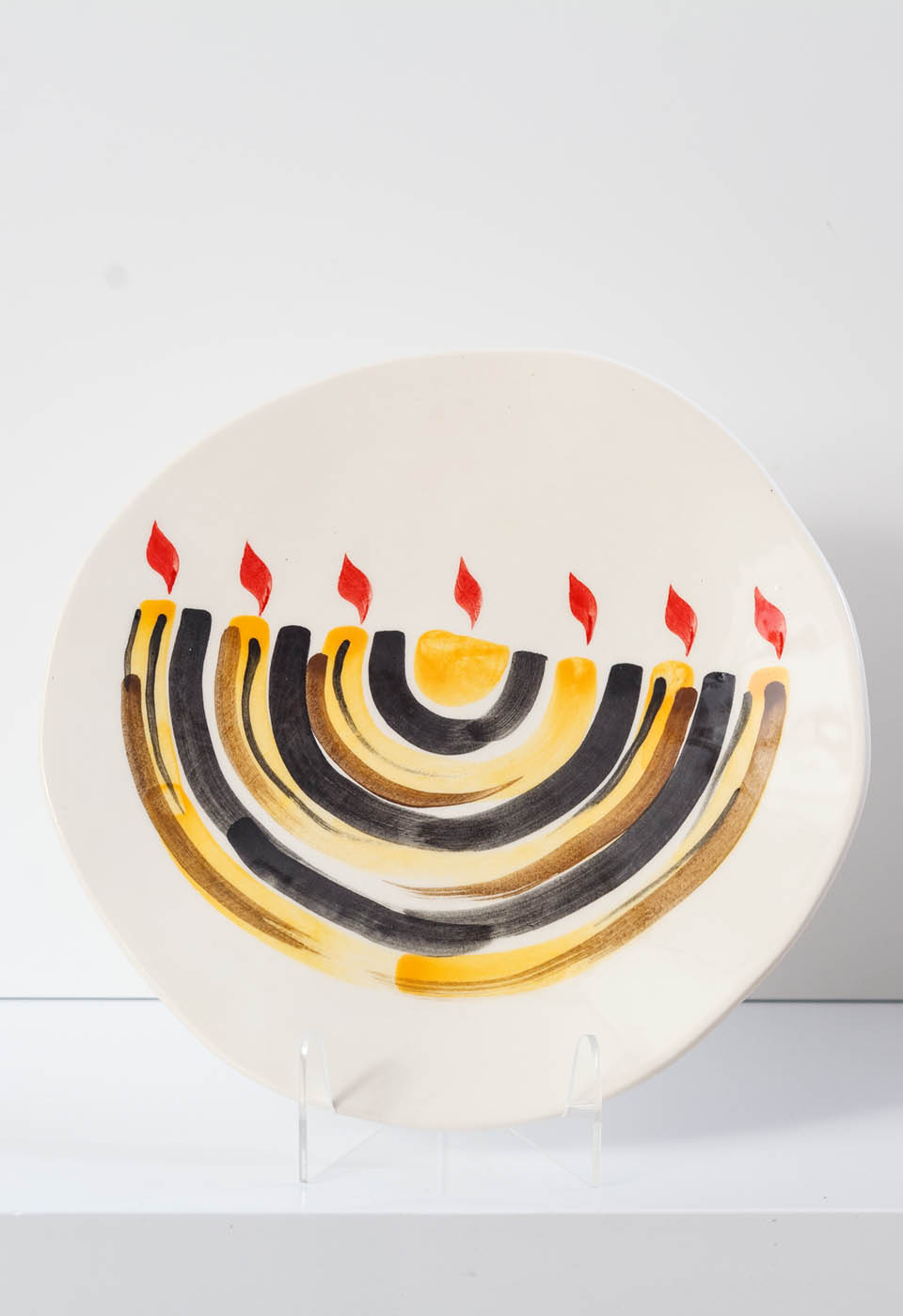 Menorah plate. The ceramic plate was treated as a painting. Menorah plate was hand-painted by Helena Czernek co-designer MI POLIN, who, together with Aleksander Prugar, developed the unique painting patterns. The plates painting are inspired by Polish graphic design of the 1960s and 1970s. This refers to the pottery factories of Włocławek and Tułowice. Made at MI POLIN and entirely manufactured in Poland.