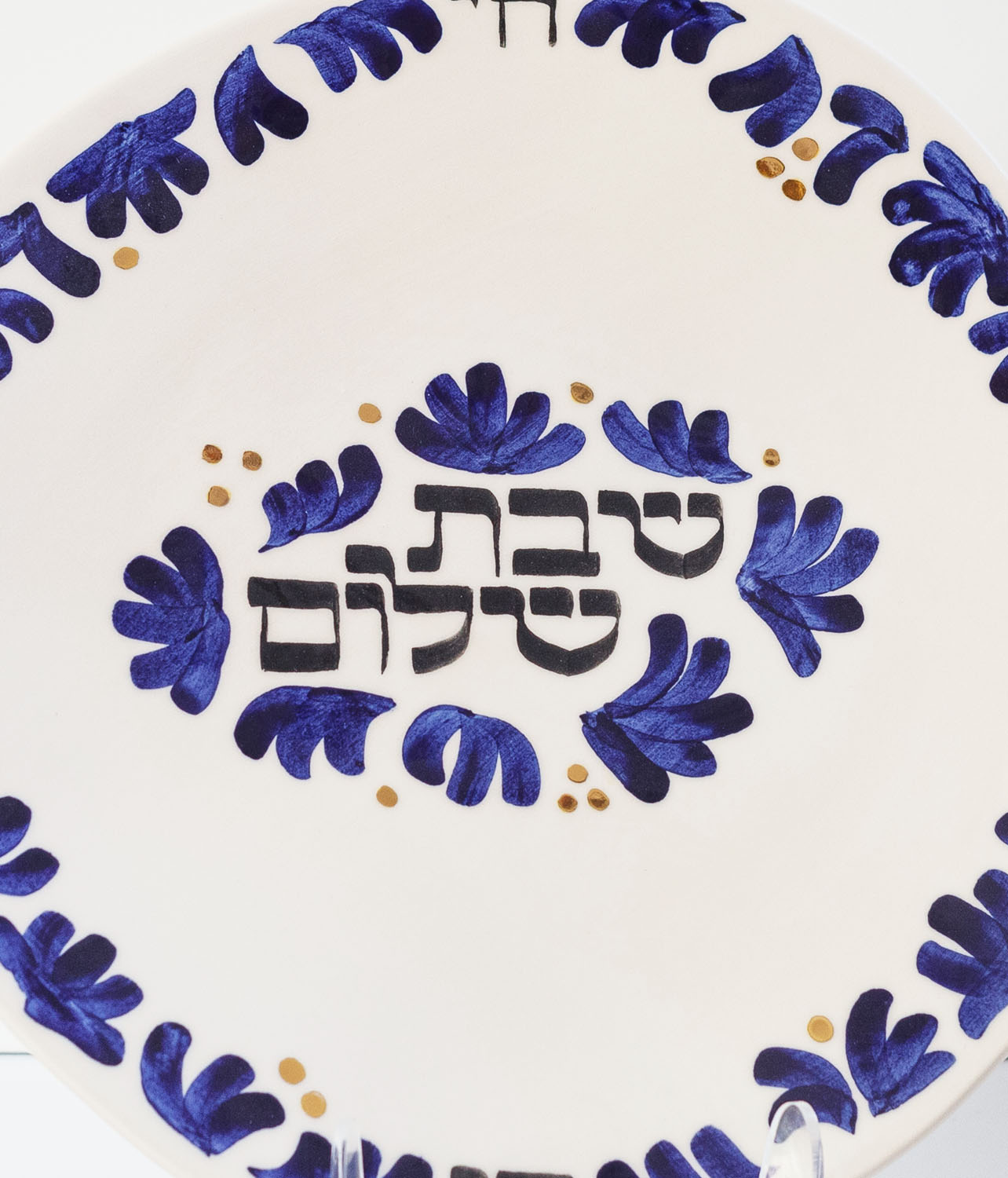 Hand-calligraphed Hebrew inscription "Shabbat Shalom" on a decorative Jewish plate