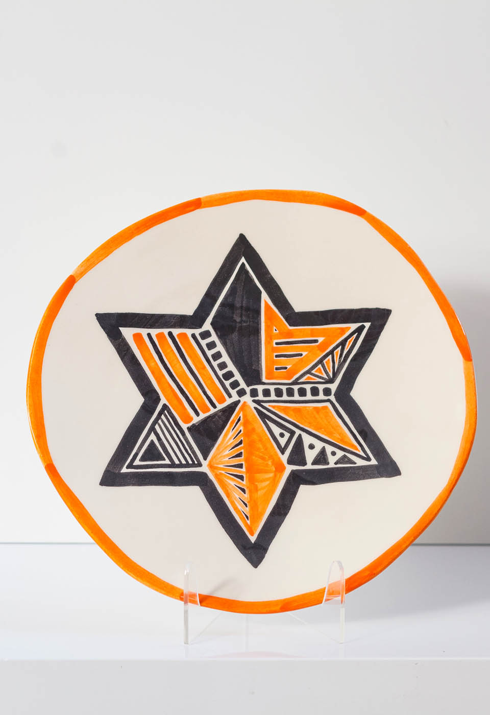 Star of David. The ceramic plate was treated as a painting. The Star of David was hand-painted by Helena Czernek co-designer MI POLIN, who, together with Aleksander Prugar, developed the unique painting patterns. The plates painting are inspired by the Cubist style and Polish graphic design of the 1960s and 1970s. Made at MI POLIN and entirely manufactured in Poland.