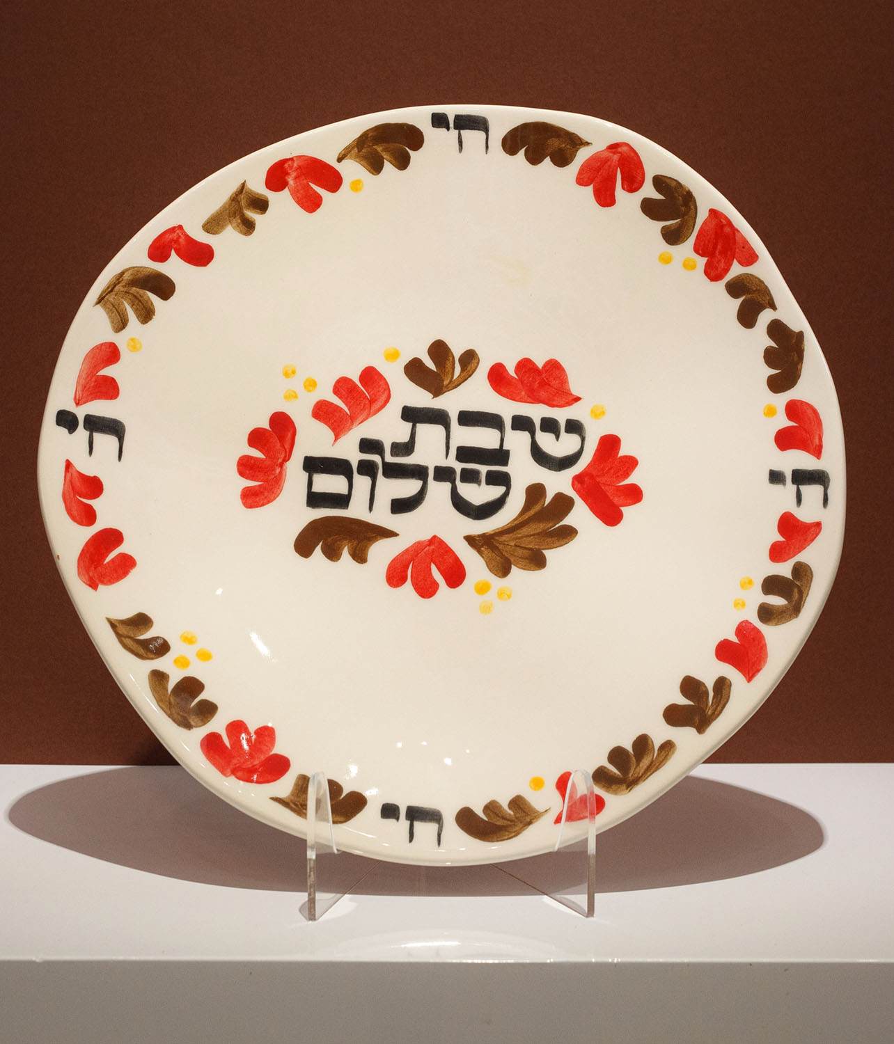 Hand-calligraphed Hebrew inscription "Shabbat Shalom" on a decorative Jewish plate